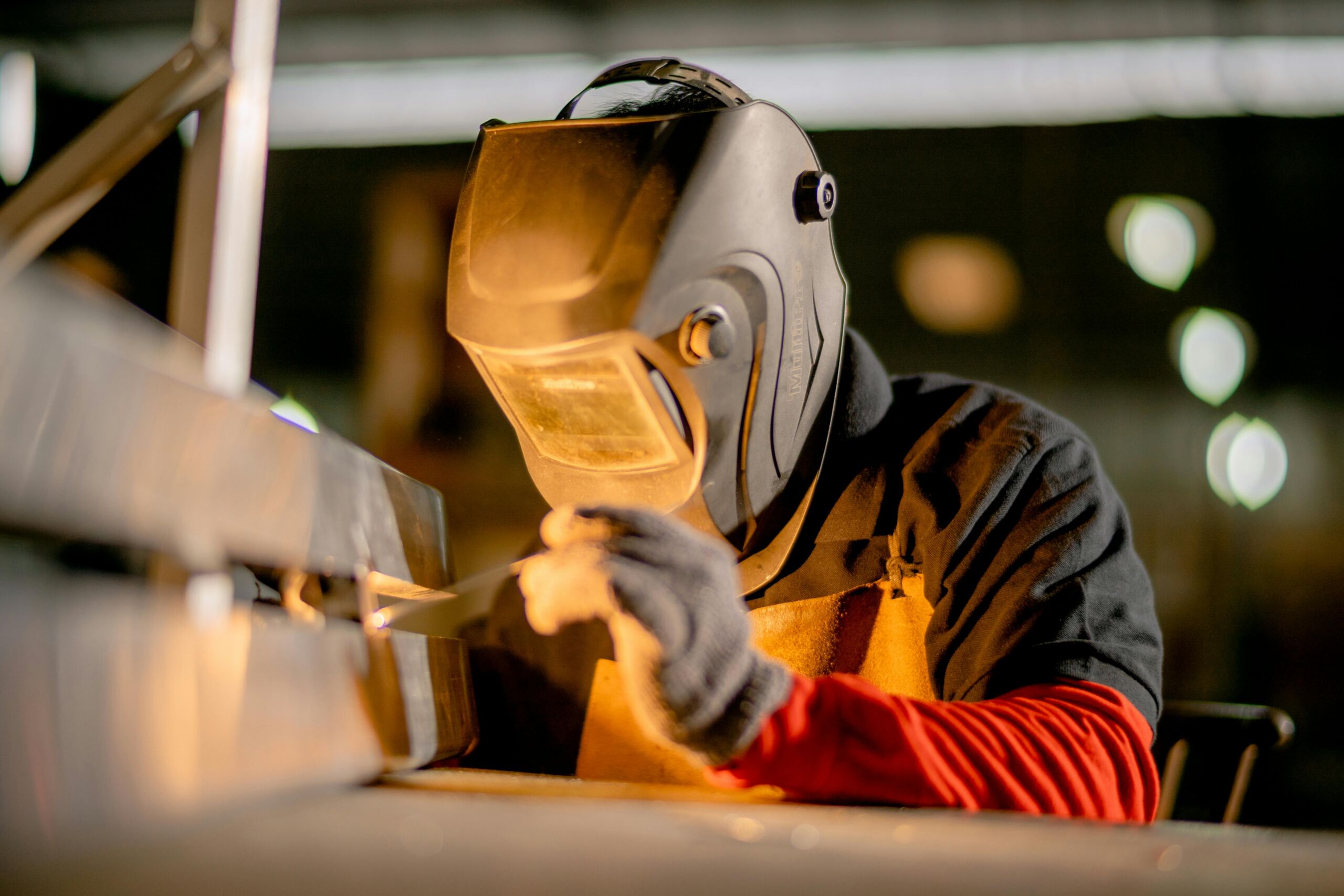 A skilled Admalite welder in action, welding a component of a 3-ton gantry crane in a manufacturing facility in the USA. The image captures the precision and expertise involved in the assembly process, emphasizing the commitment to safety, functionality, and support of American manufacturing standards.